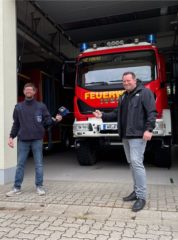 Florian Fahrtmann und Milan Fulst stehen vor einem Feuerwehrauto in der Garage