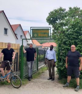 Dr. Karamba Diaby steht mit Florian Fahrtmann und anderen Personen in einer Gartenspartenanlage