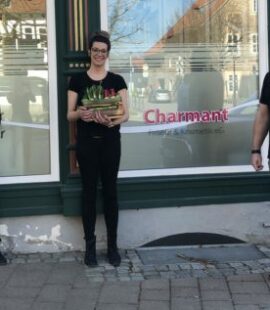 zwei Frauen und ein Mann stehen vor einem Schaufenster, eine hat ein Geschenk in den Händen