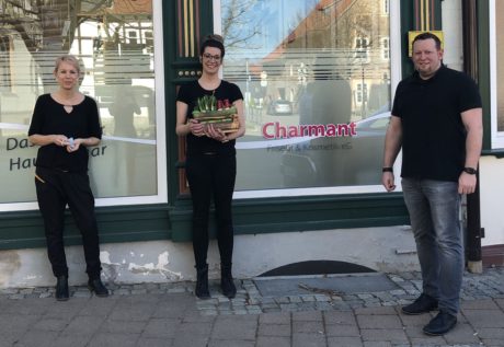 zwei Frauen und ein Mann stehen vor einem Schaufenster, eine hat ein Geschenk in den Händen