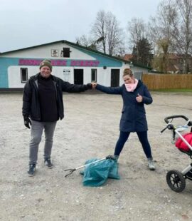2 Personen stehen in großem Abstand vor einem mit Müll befüllten blauen Plastiksack