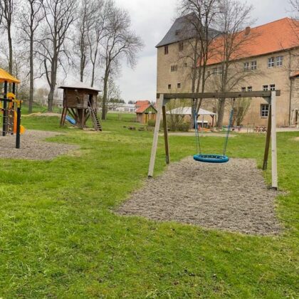 Im Vordergrund ein Speilplatz mit einem alten Steinhaus im Hintergrund