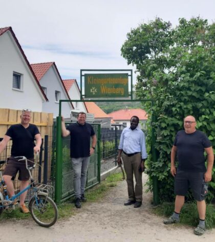 Dr. Karamba Diaby steht mit Florian Fahrtmann und anderen Personen in einer Gartenspartenanlage