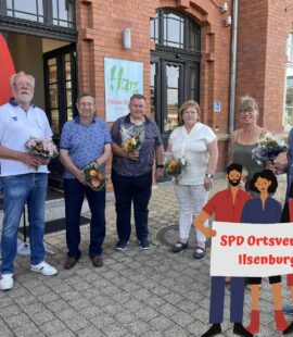 mehrere Personen stehen vor dem Bahnhof Ilsenburg mit einem Strauß Blumen in den Händen