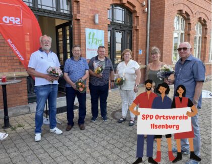 mehrere Personen stehen vor dem Bahnhof Ilsenburg mit einem Strauß Blumen in den Händen