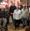 nehrere Personen stehen vor einen Aufsteller mit SPD Logo