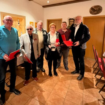 mehrere Menschen stehen im Halbkreis und halten ihre Urkunden in den Händen und lächeln in die Kamera